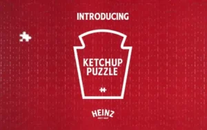 Immagine del puzzle creato da Heinz cui manca un pezzo sul lato sinistro, poco lontano dal bordo, e si vedono i contorni di tutti i tasselli rossi. Al centro, in bianco, la scritta "Introducing Ketchup Puzzle" seguita dal logo di Heinz.